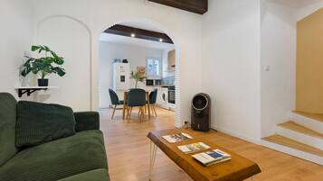 A modern living room with a green sofa, a wooden coffee table with magazines, and a potted plant.