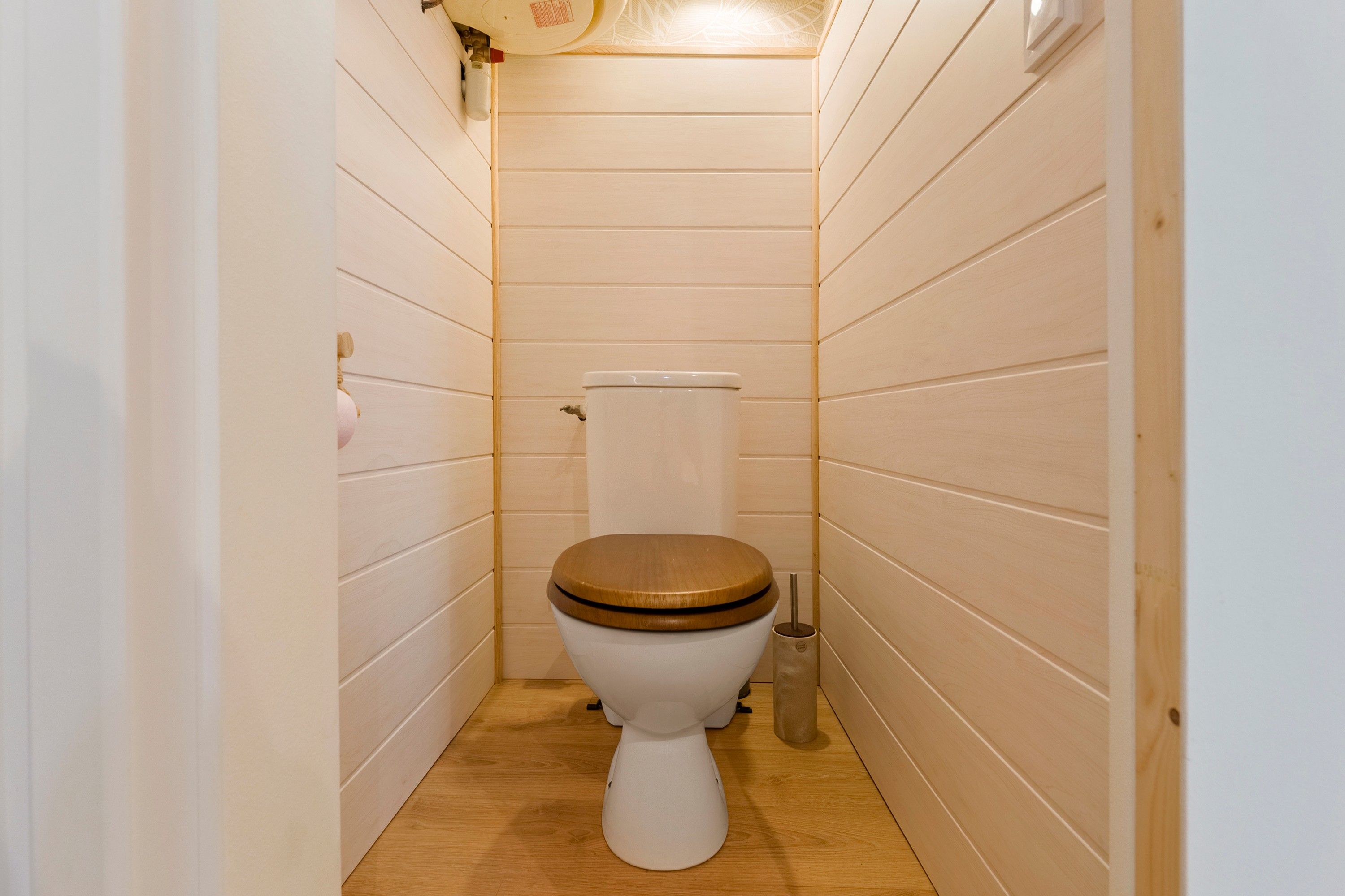 Een kleine, smalle badkamer met houten wanden en een houten vloer.