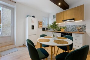 Una cocina moderna con armarios blancos, horno empotrado y un comedor con una mesa redonda y sillas.