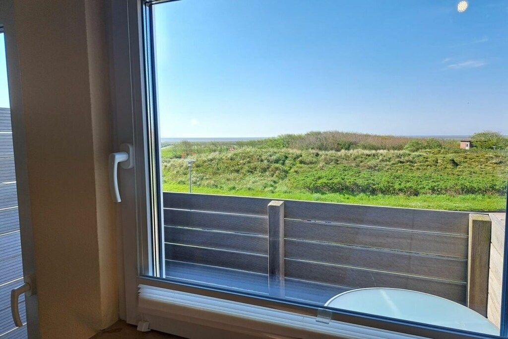 A room with a large window overlooking a grassy landscape.