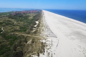 An aerial view of a coastal area with a beach, a road, and a settlement in the distance. - Holiday apartment in Juist with swimming pool (Juist)