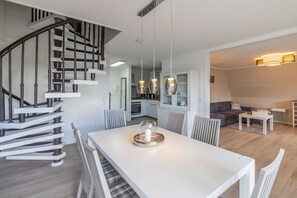 Ein modernes Interieur mit Treppe, Essbereich, Küche und Wohnbereich.