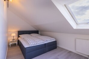 Une chambre à coucher avec un lit, une table de chevet, une fenêtre et un radiateur.