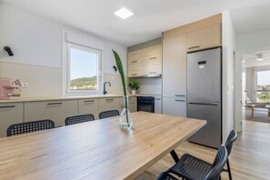 Eine moderne Küche mit einem Holztisch, Stühlen, einem Kühlschrank und einem Fenster mit Blick.