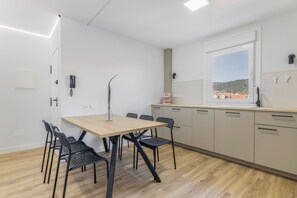 Eine moderne Küche mit einem Holztisch und Stühlen, einem Fenster mit Blick und einer kleinen Pflanze auf dem Tisch.