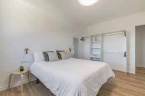 Ein modernes Schlafzimmer mit einem großen Bett, Nachttischen, einem Kleiderschrank und einem Spiegel.