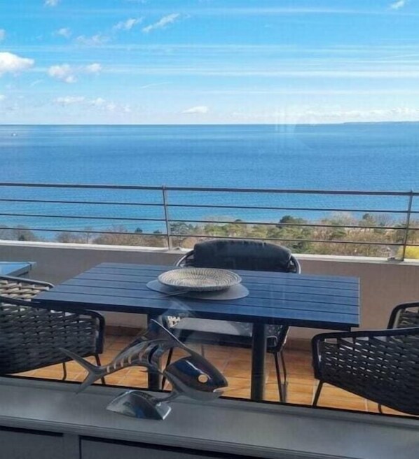 A balcony with a table and chairs, overlooking a body of water. - Holiday apartment MeerZeit (Timmendorfer Strand)