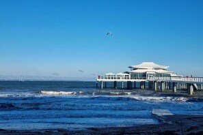 A coastal building with a white exterior, a flat roof, and a pier extending into the water. - Holiday apartment MeerZeit (Timmendorfer Strand)