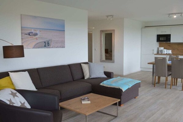 Una sala de estar moderna con un sofá, una mesa de centro y un cuadro de gaviotas en la pared.
