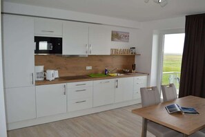 Eine moderne Küche mit weißen Schränken, einer Holzarbeitsplatte und einem Essbereich mit Tisch und Stühlen.