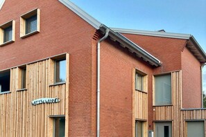 A modern building with a brick facade, wooden slats, and a sign that reads 'WATTIN WINNER.' - WATT MOIJ on the ground floor with garden (Borkum)