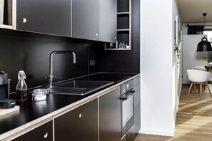 A modern kitchen with a black countertop, stainless steel appliances, and a built-in oven. - WATT MOIJ on the ground floor with garden (Borkum)