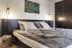 A modern bedroom with a large bed, a headboard, and a wall-mounted light fixture. - WATT MOIJ on the ground floor with garden (Borkum)
