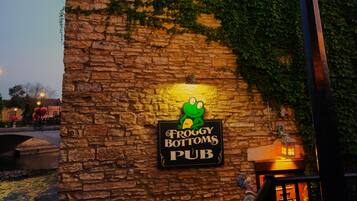 A stone wall with a pub sign, a metal fence, and a lamp post.