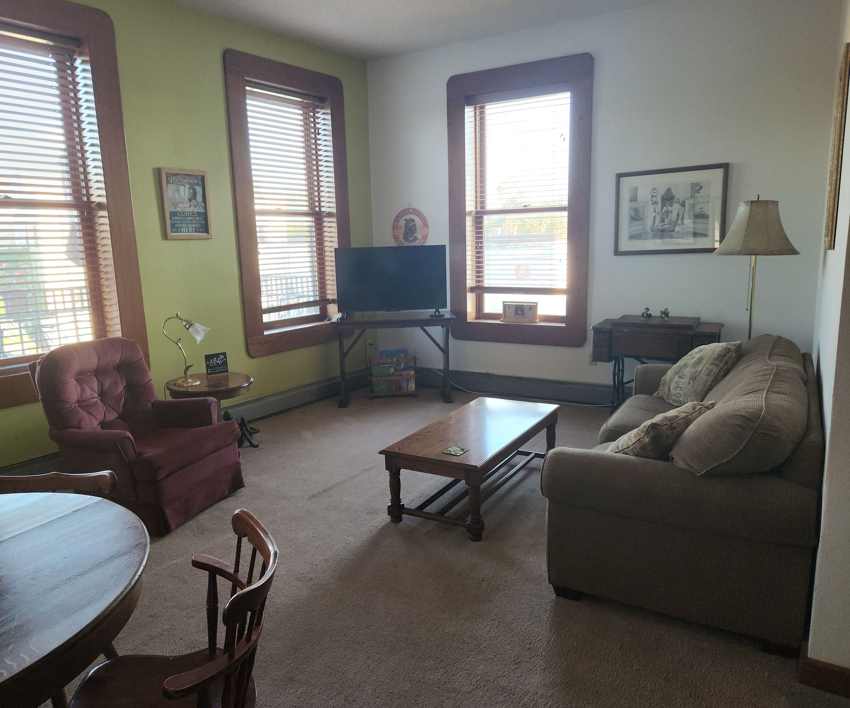 A living room with a television, a sofa, a chair, a table, and a lamp.