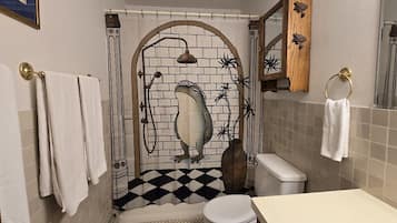 A bathroom with a shower, toilet, and a decorative frog mural.