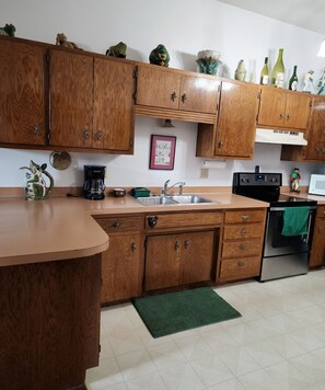 A kitchen with wooden cabinets, a sink, a coffee maker, and a microwave.