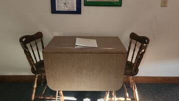 A room with a table and two chairs, a framed map on the wall, and a light switch.