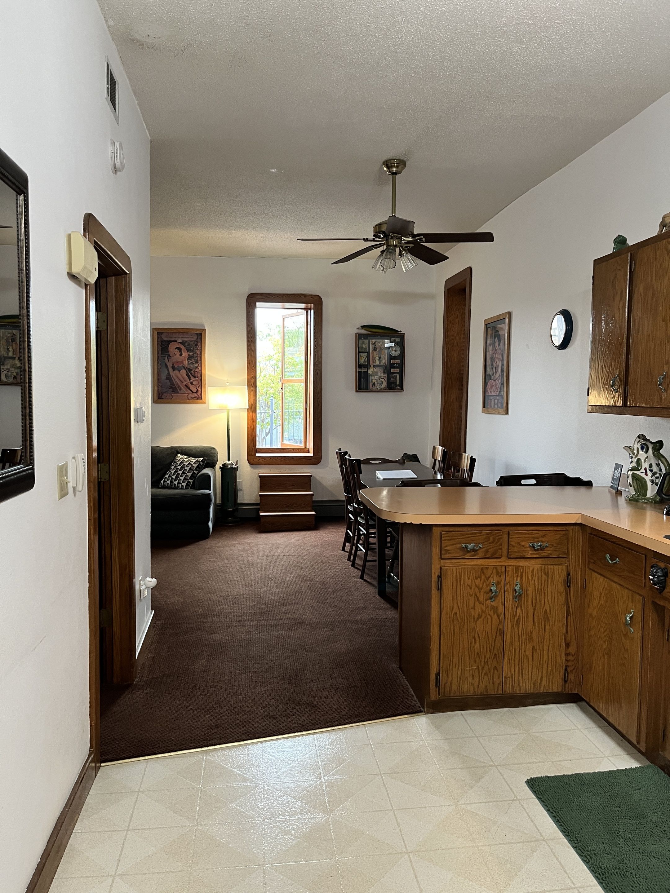 A kitchen with a central island, wooden cabinets, a ceiling fan, and a dining area with a table and chairs.