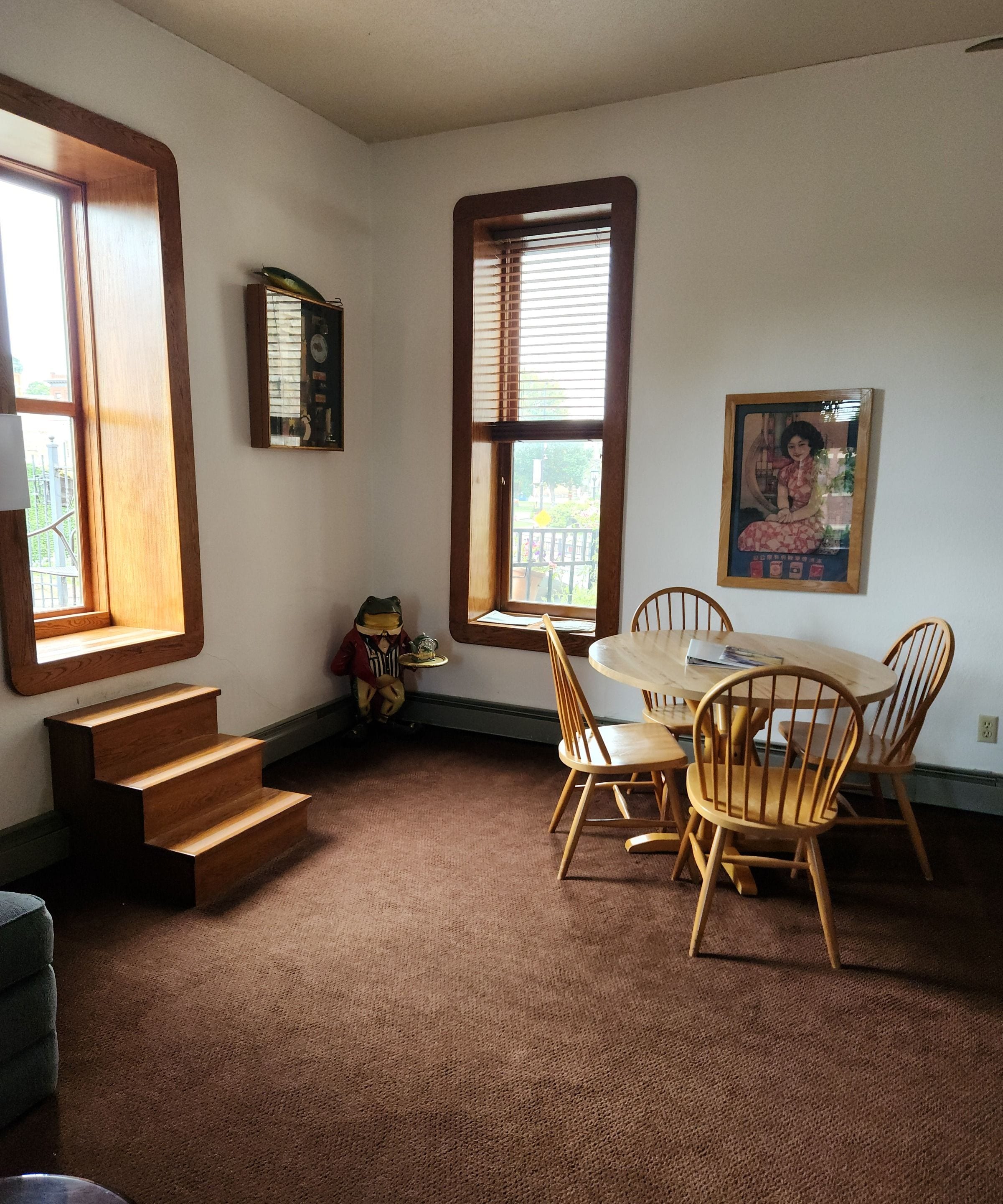 A room with a dining table, chairs, a staircase, and a large window.