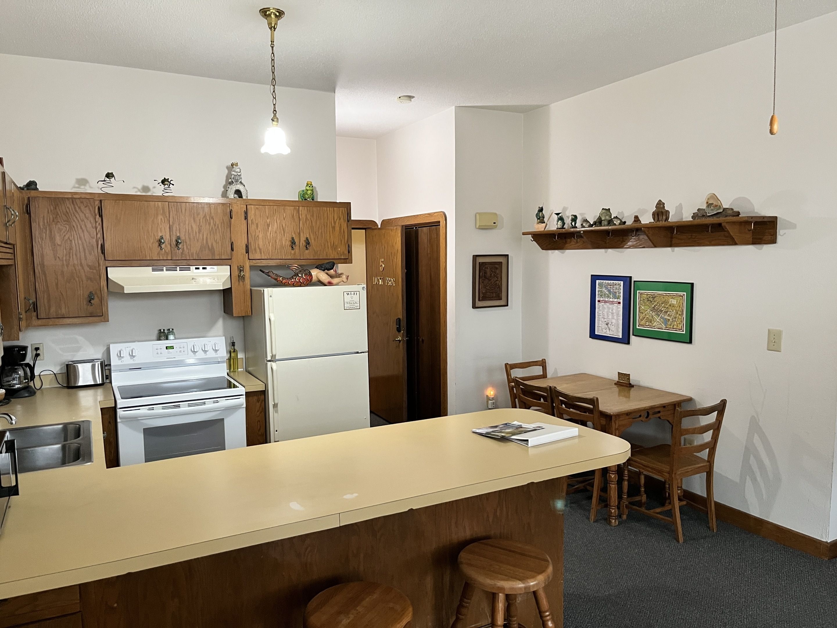 Cocina funcional con gabinetes de madera, estufa blanca, refrigerador y comedor con mesa y sillas.