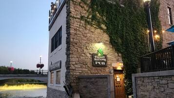 Ein Steinhaus mit einem Schild für 'Froggy Bottoms Pub' und einem Metallgeländer davor.