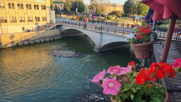 A river with a stone bridge, potted flowers, and buildings in the background.
