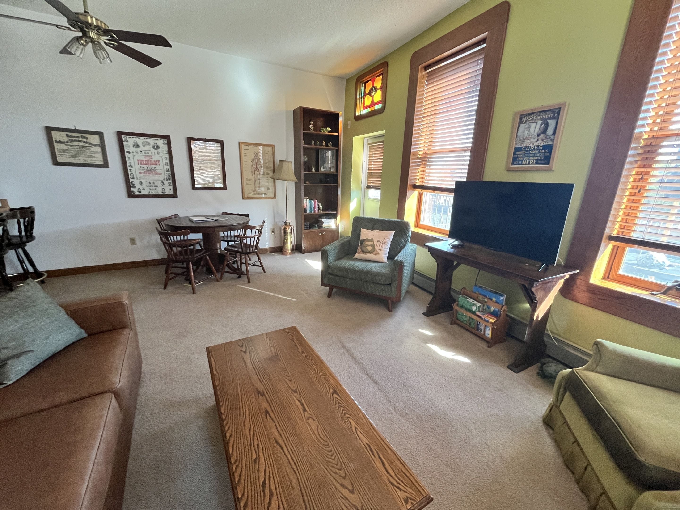 A living room with a sofa, armchair, coffee table, TV stand, and a bookshelf.