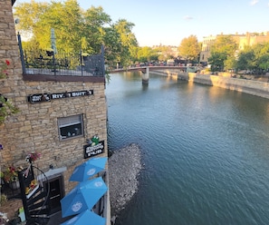 A riverside view with a stone building featuring signs for 'Froggy Bottoms Pub' and 'River Suit $'.