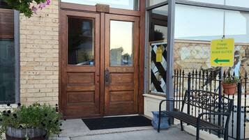 A double door entrance with a sign above reading 'FROGGY BOTTOMS RIVER SUITES' and a contact number.