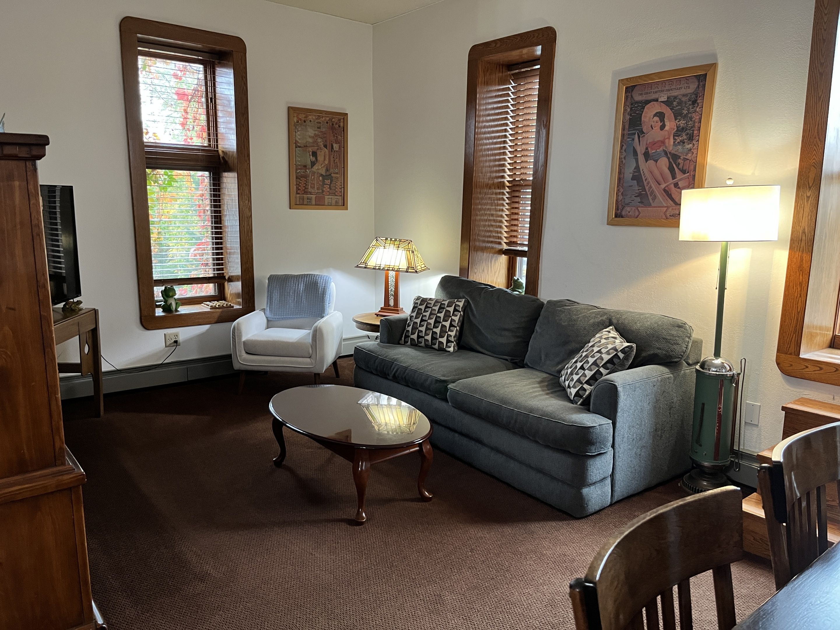 A living room with a sofa, armchair, coffee table, and a lamp.