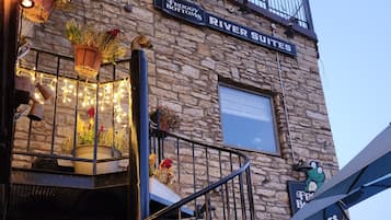 Un immeuble avec une façade en pierre, une enseigne indiquant « River Suites », et un escalier doté d’une rampe en métal.