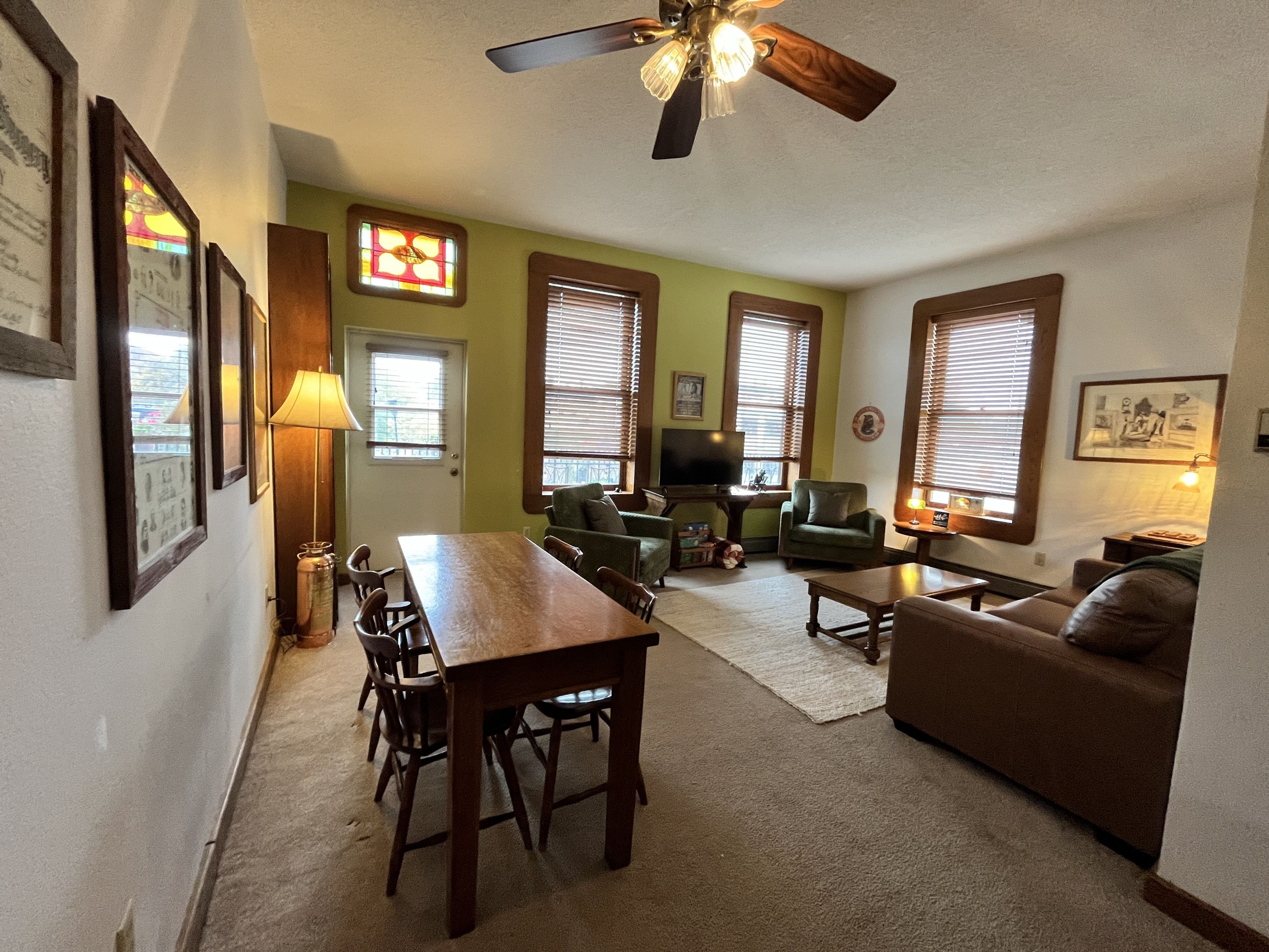 A living room with a dining table, chairs, a sofa, and a television.