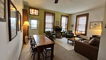 A living room with a dining table, chairs, a sofa, and a television.