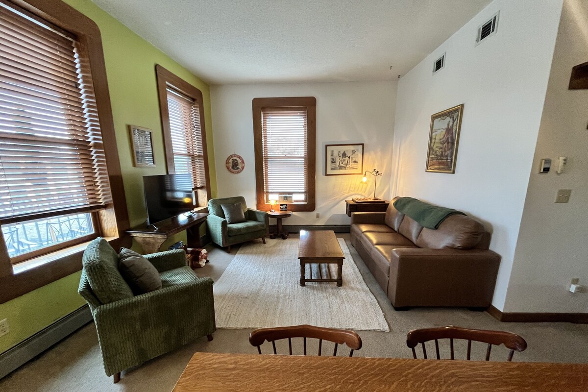 A living room with a sofa, armchairs, a coffee table, and a TV.