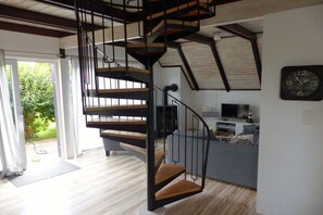 A modern interior with a spiral staircase, a flat-screen TV, and a dining area. - Holiday home with 3 bedrooms (Wurster Nordseeküste, Dorum- Neufeld)