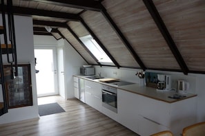 A modern kitchen with a sloped ceiling, built-in appliances, and a view of the outdoors. - Holiday home with 3 bedrooms (Wurster Nordseeküste, Dorum- Neufeld)