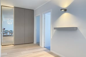 A hallway with a sliding door, a light fixture, and a glimpse of a dining area with chairs and a table. - Holiday apartment with 2 bedrooms (Timmendorfer Strand)