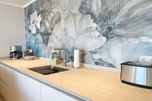 A modern kitchen with a marble backsplash, stainless steel appliances, and a built-in toaster. - Holiday apartment with 2 bedrooms (Timmendorfer Strand)