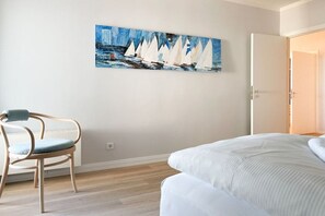A bedroom with a bed, a chair, and a painting on the wall. - Holiday apartment with 2 bedrooms (Timmendorfer Strand)