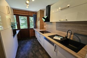 Cozinha moderna com pia preta, armários brancos e janela com cortinas.