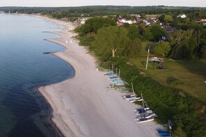 An aerial view of a beach with boats, a flag, and houses in the background. - Holiday home with 3 bedrooms (Sierksdorf)