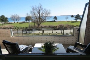 Un balcón con vistas al mar, una mesa con una planta y dos sillas.