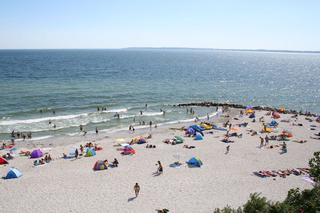 A beach with people, tents, and umbrellas.