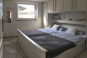 A single-bed room with a window, a mirror, and built-in shelves. - Strandhus (formerly Sternenhimmel) (Lübeck)
