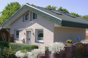 A two-story house with a sloped roof, a front door, and a small porch. - Strandhus (formerly Sternenhimmel) (Lübeck)