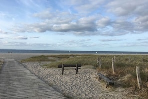 A wooden boardwalk leading to a sandy beach with a bench and wooden fence. - Strandhus (formerly Sternenhimmel) (Lübeck)