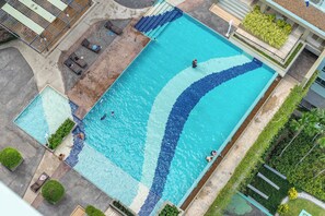 En stor rektangulär swimmingpool med en kant av kakel, omgiven av en betongplattform och några solstolar.