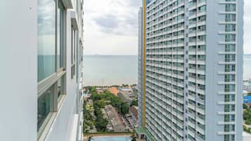 A high-rise building with a view of the sea and a swimming pool area.