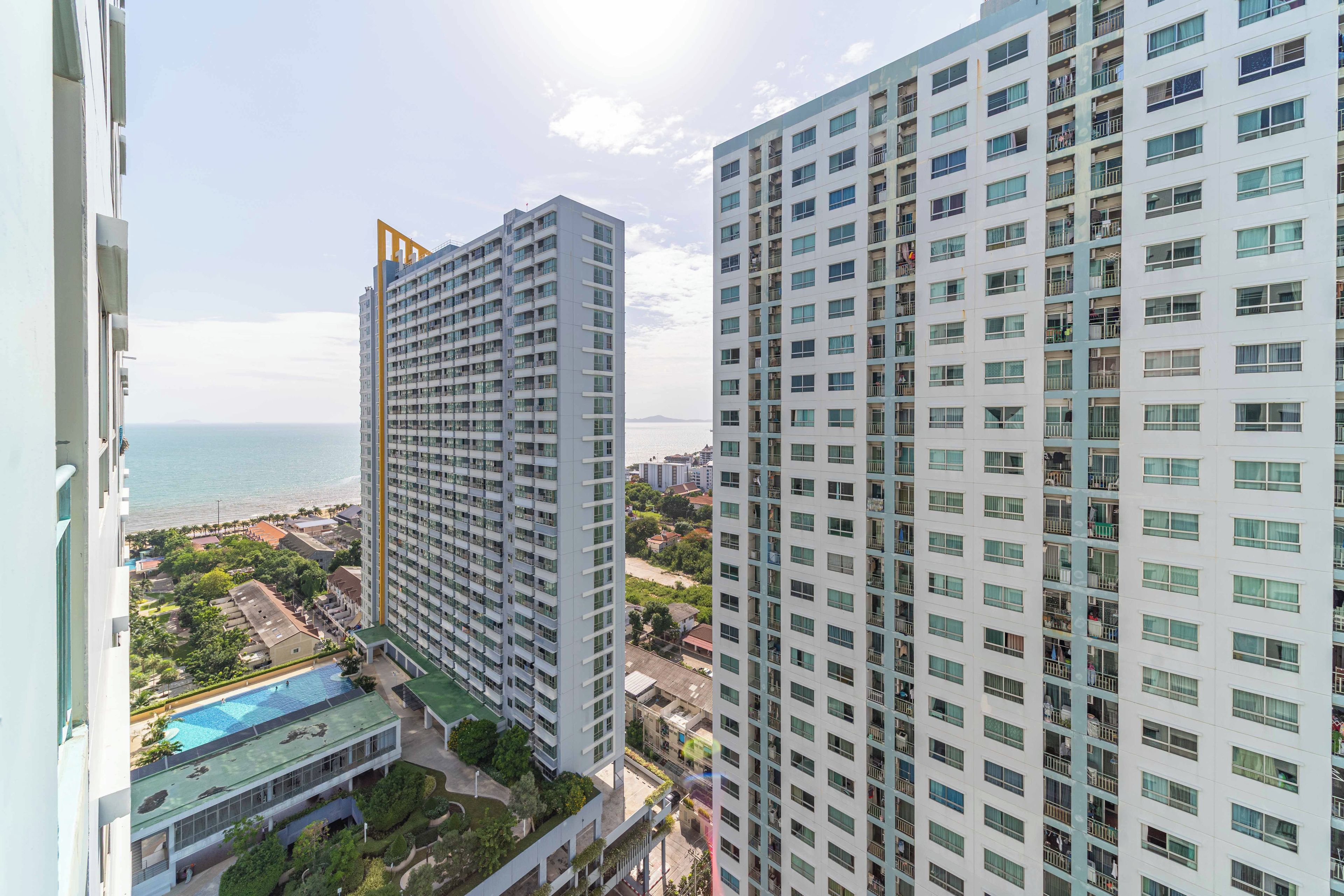 Un edificio de gran altura con varios pisos, una piscina y vista al mar.